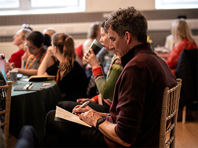 person reading book on brown and beige textile